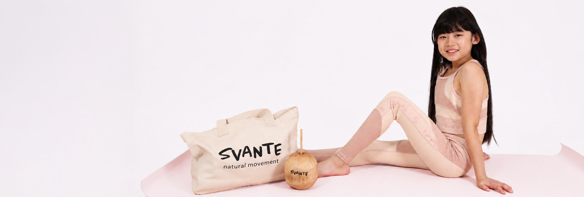 Chinese girl sitting on orange yoga matt with organic cotton Svante Tote bag and wearing natural material sports leggings and sports crop top