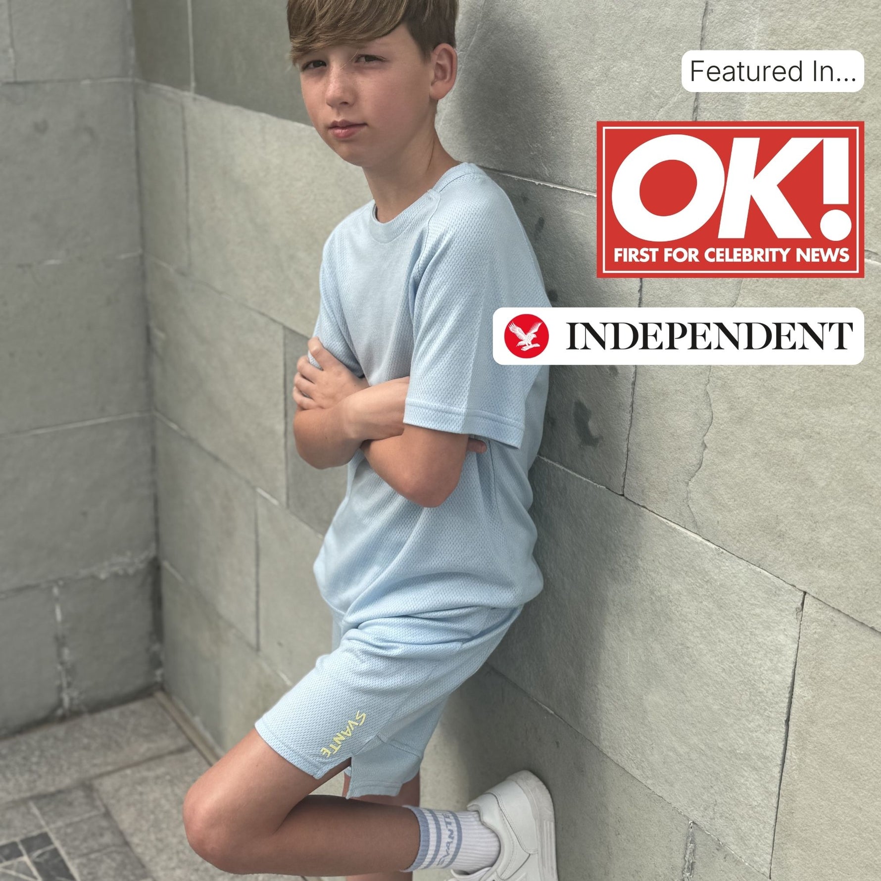 Boy in light blue natural material sportsoutfit leaning against a tiled wall with OK! and Independent logos.