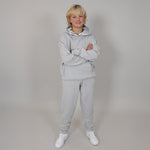 blonde hair boy wearing a grey relaxed organic cotton tracksuit with a mellow background