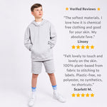 Boy wearing a grey organic cotton hoodie and grey organic cotton jersey shorts with positive reviews displayed on a white background. 