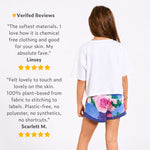 Girl wearing a white organic cotton crop t-shirt and blue floral sports shorts with verified customer reviews on a white background. 