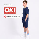 Young boy in a matching organic cotton navy T-shirt and Jersey shorts outfit with OK! and Independent logos on a white background. 