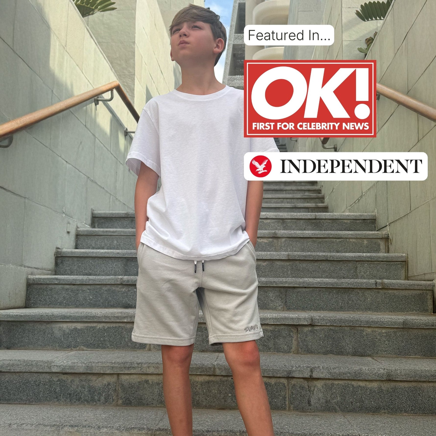 Boy standing on stairs wearing regenerative cotton jersey shorts and a white regenerative cotton t-shirt with 'OK!' and 'Independent' logos displayed. 
