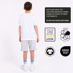 Boy wearing a white organic cotton t-shirt and grey organic cotton jersey shorts with certification logos on a white background. 
