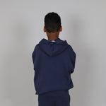 10 year old child with back to camera  wearing a navy regenerative cotton blue hoodie in a studio. 