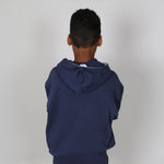 Young boy wearing an organic certified navy blue hoodie with a white logo on a plain background. 