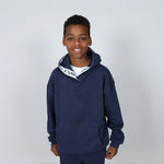 Boy aged 11 wearing a navy blue regenerative cotton  hoodie with a 'Svante' white logo on a grey background. 