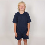 Young boy wearing a natural material navy blue sports outfit against a plain background