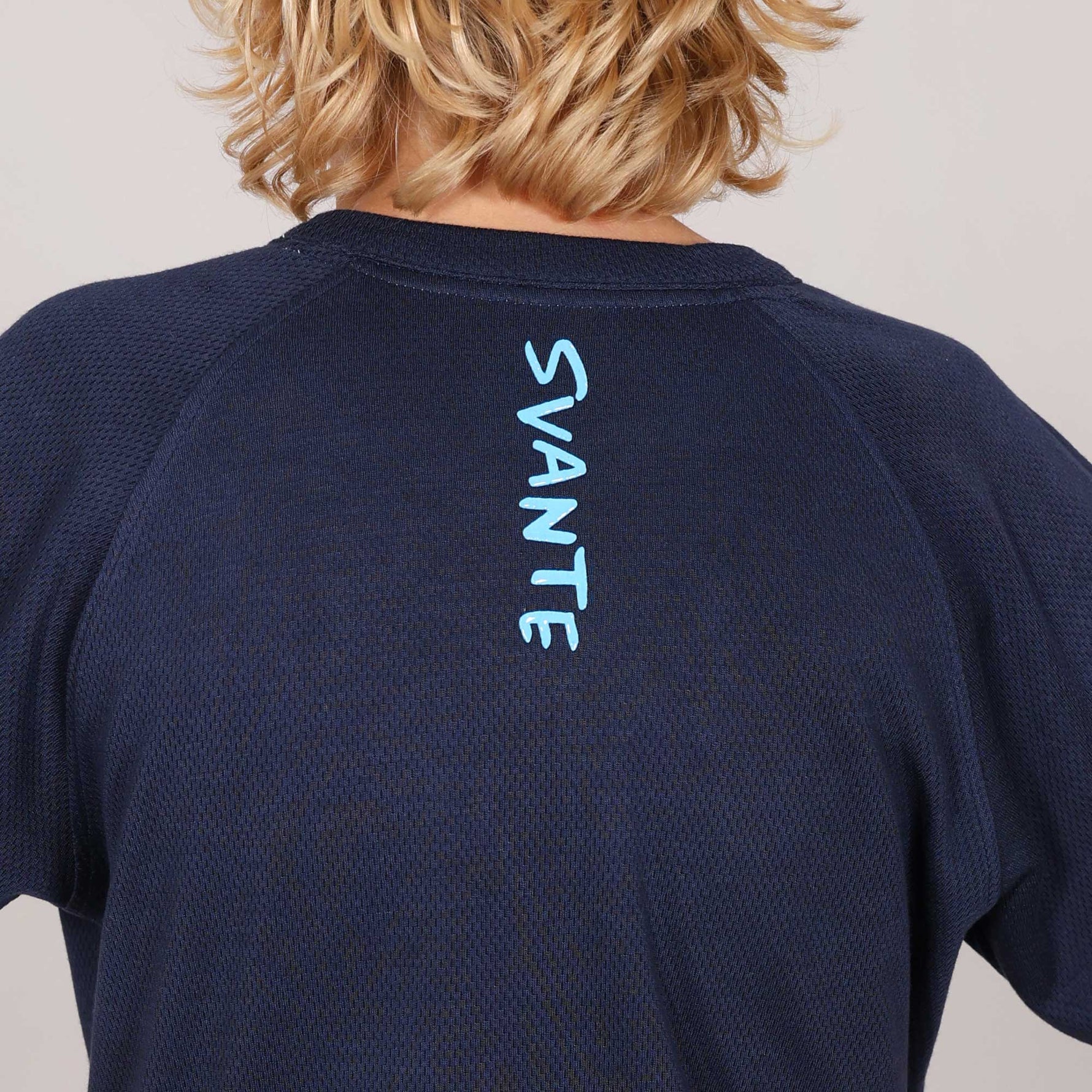 Close up image of Navy blue t-shirt with 'SVANTE' branding on the back, worn by a kid.