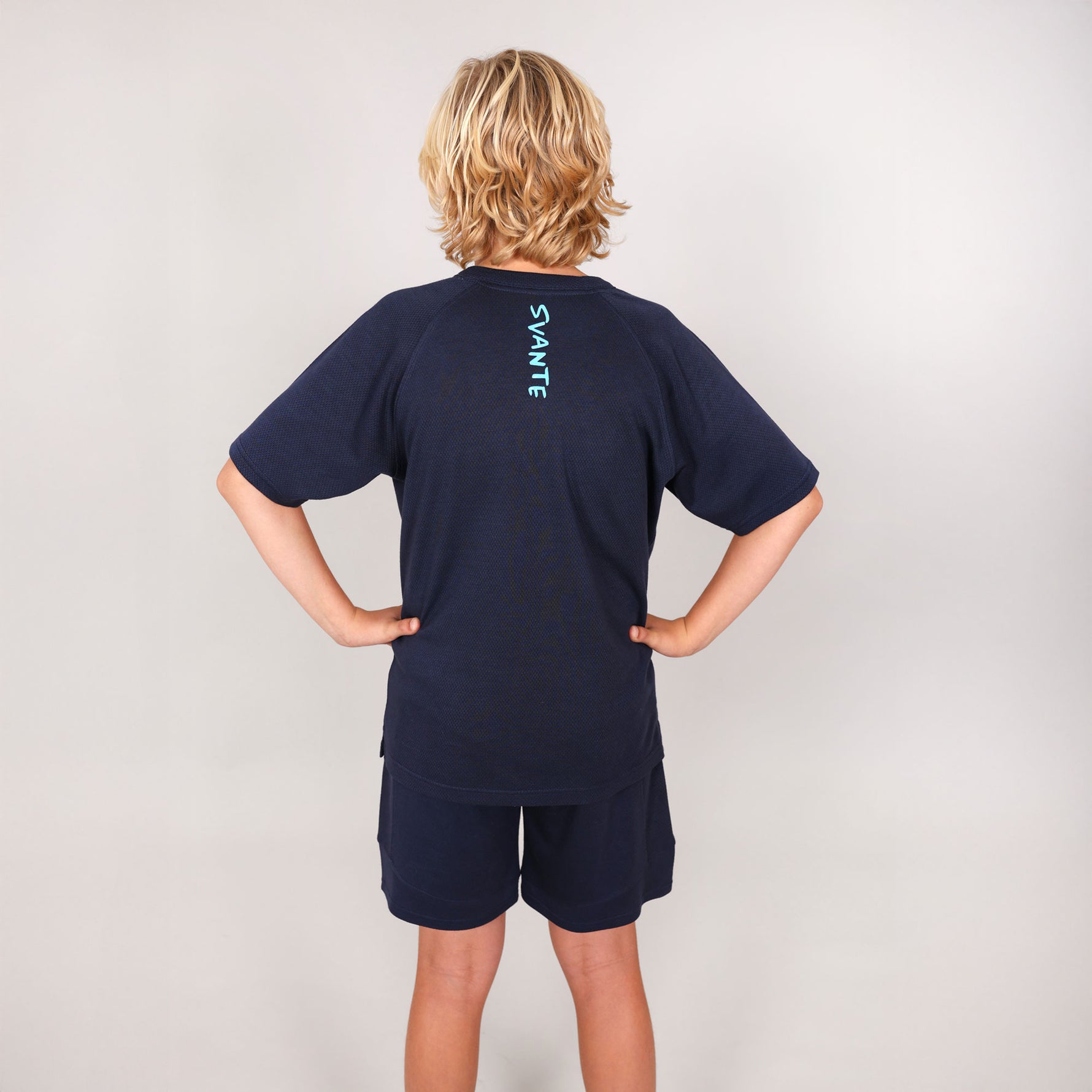 Child wearing a navy blue t-shirt and shorts set with 'Svante' branding on the back of t-shirt on a light grey background
