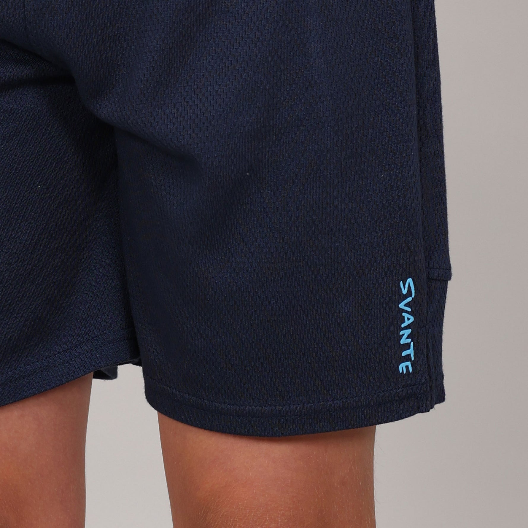 Detail close up of Navy sports shorts with 'SVANTE' branding on a neutral background