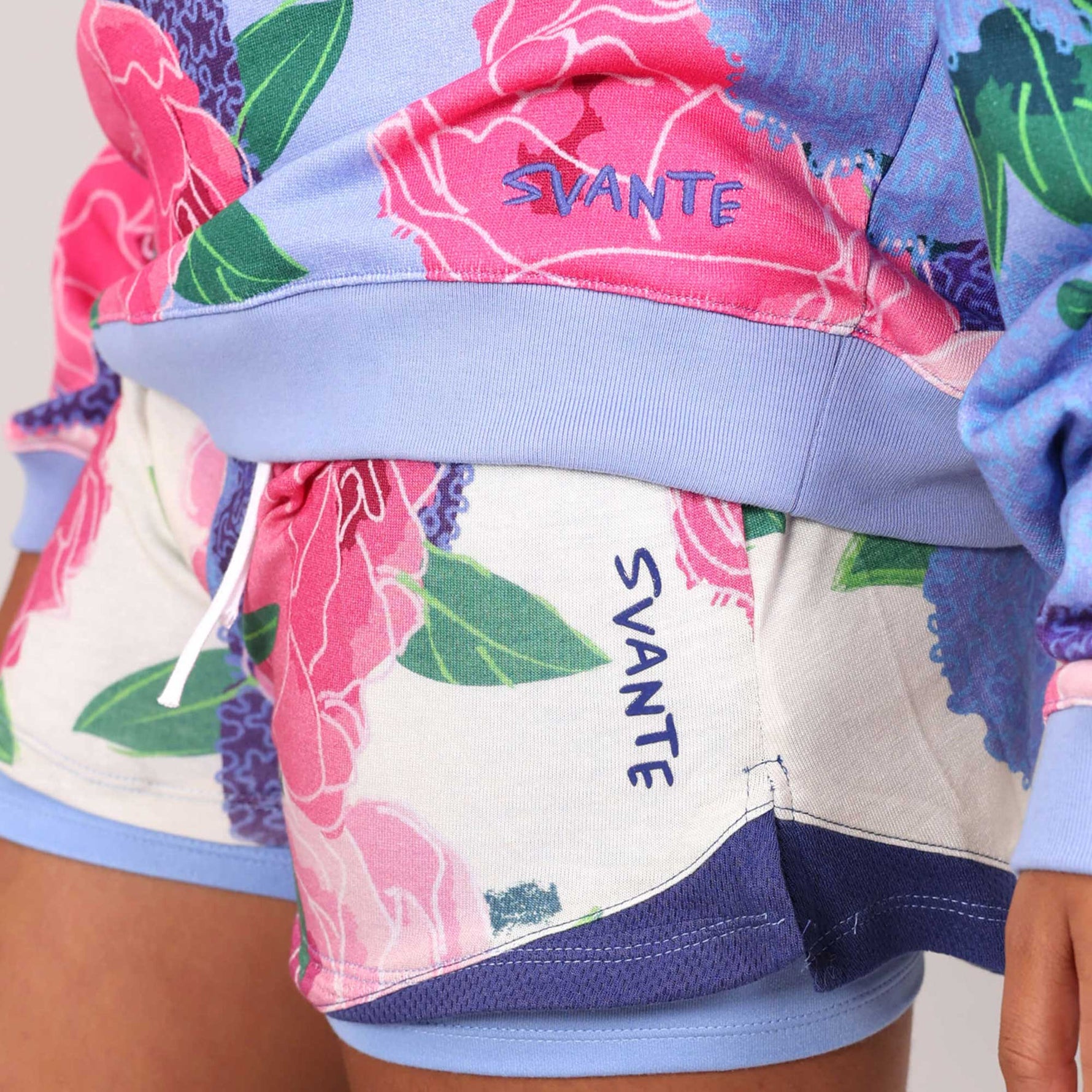 Floral shorts and hoodie outfit with 'SVANTE' logo detail branding on a girl in a studio. 