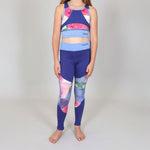 Girl wearing a colourful blue and floral sports crop-top and matching floral sports leggings set on a plain background. 