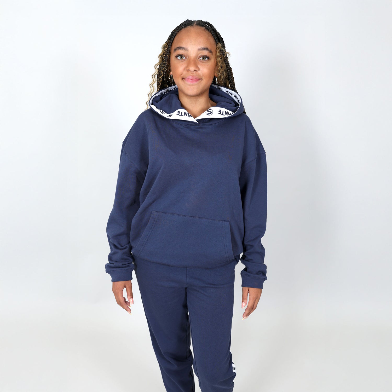 Teenage girl wearing a navy blue organic hoodie and joggers set on a white background. 