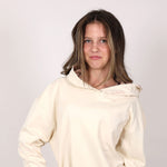 Close up front pictures of girl wearing a cream-coloured hoodie with 'Svante' branding on hood, against a pale grey background. 